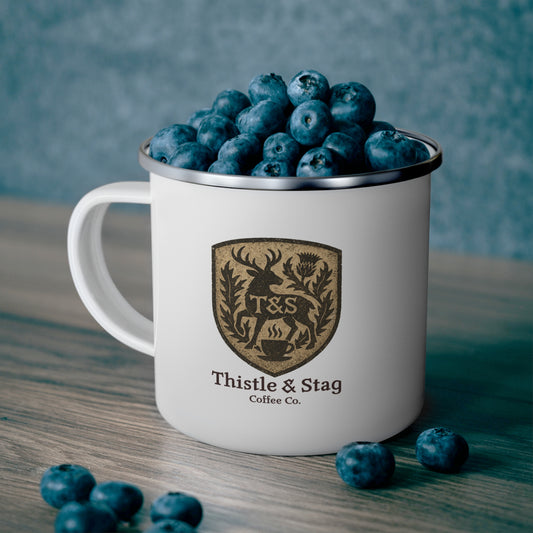 White mug with 'Thistle & Stag Coffee Co.' logo filled with blueberries on a wooden surface.