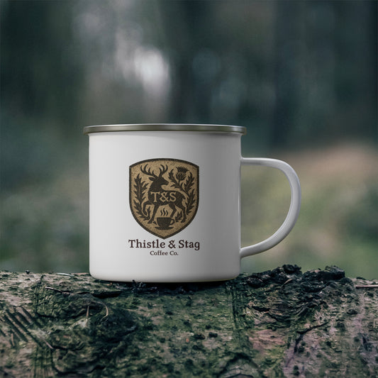 White mug with Thistle & Stag Coffee Co. logo on a wooden log with a forest background