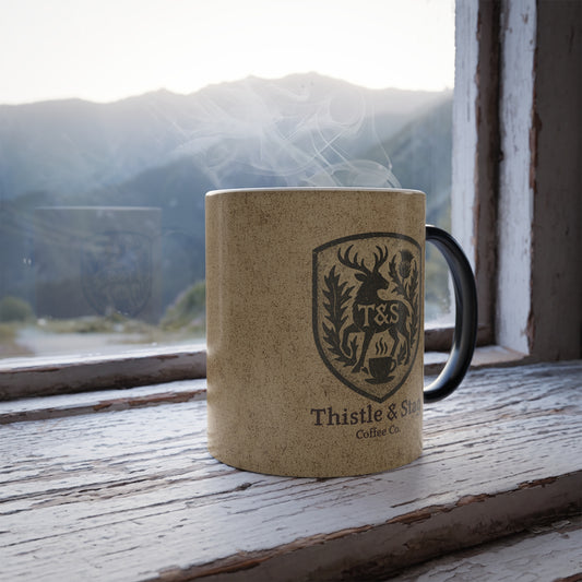 Brown mug with a "Thistle & Stag" logo and text on a wooden surface with a mountain view in the background