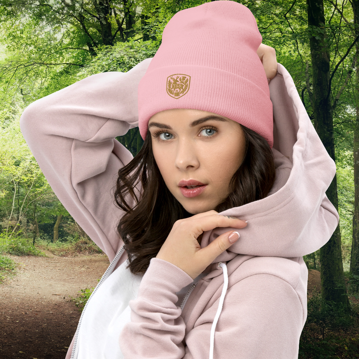 Woman wearing a pink beanie with a Thistle & Stag Coffee Co. logo and pink hoodie in a forest setting