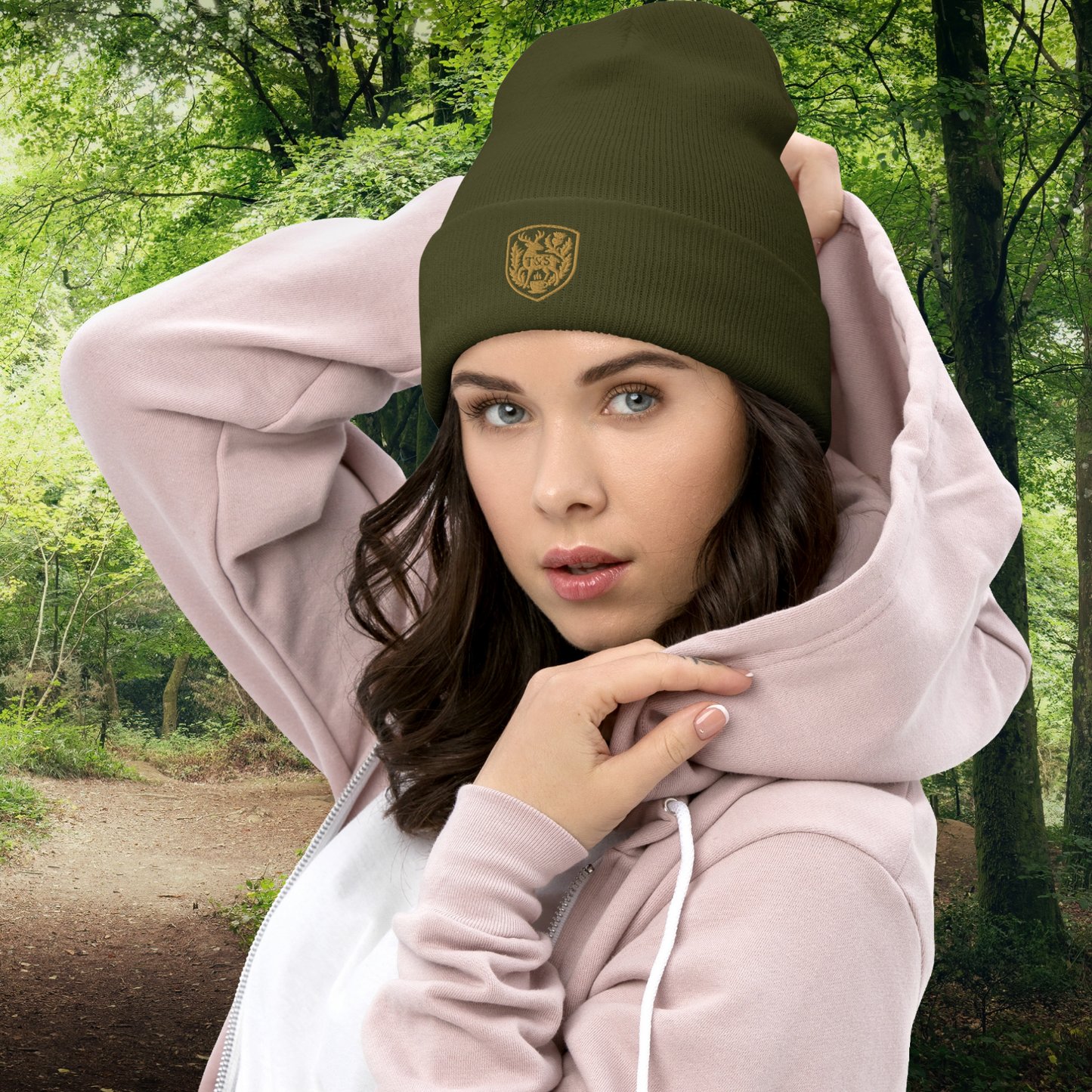 Woman wearing a green beanie with a Thistle & Stag Coffee Co. logo and pink hoodie in a forest setting
