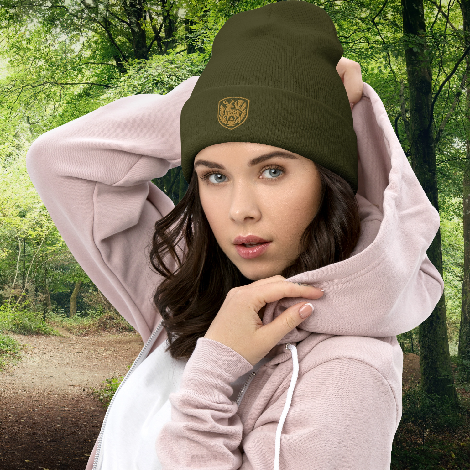 Woman wearing a green beanie with a Thistle & Stag Coffee Co. logo and pink hoodie in a forest setting