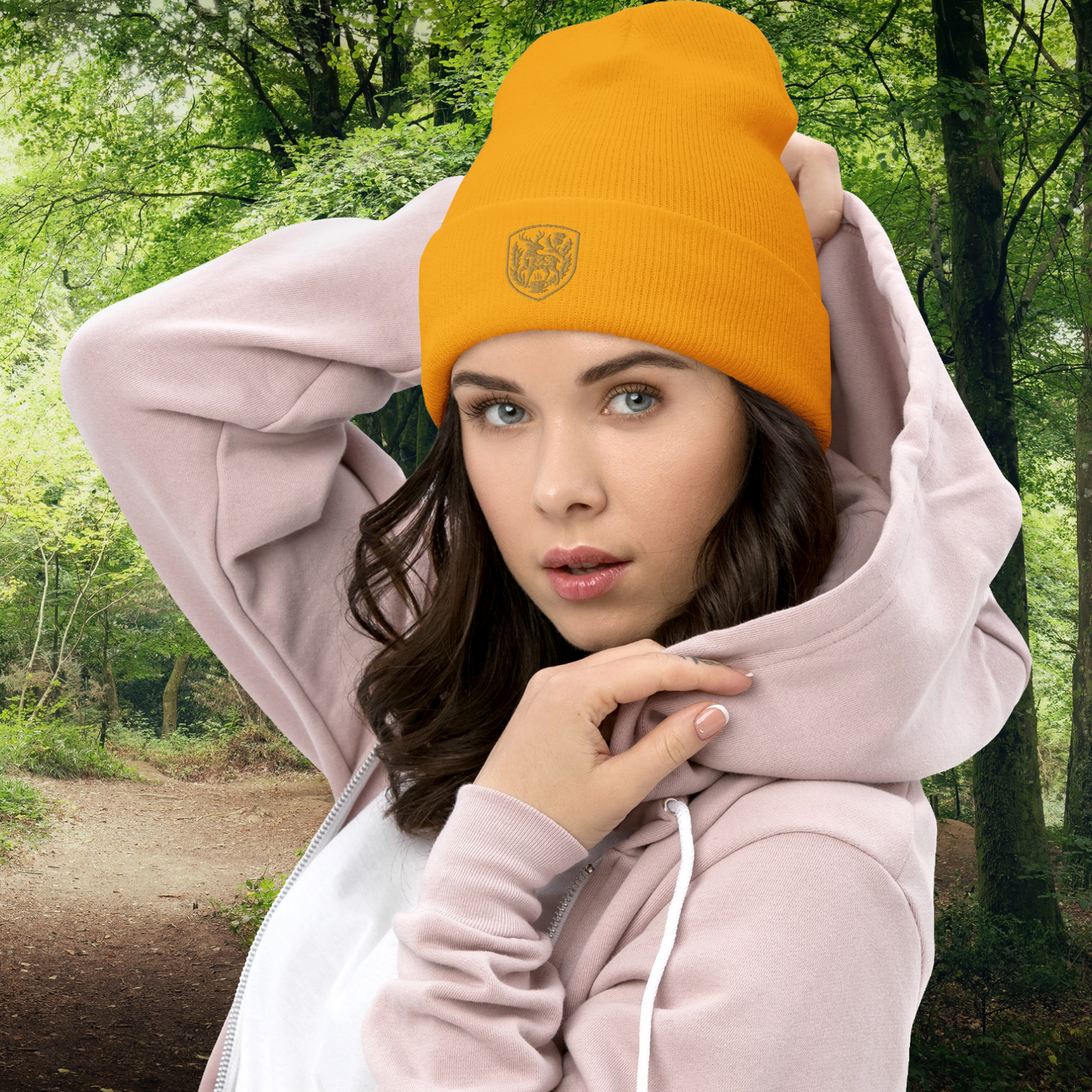 Person wearing a yellow beanie with a Thistle & Stag Coffee Co. logo and pink hoodie in a forest setting
