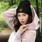 Woman wearing a black beanie with a Thistle & Stag Coffee Co. logo and pink hoodie in a forest setting
