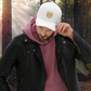 Person wearing a white cap with a Thistle & Stag Coffee Co. logo in a forest setting