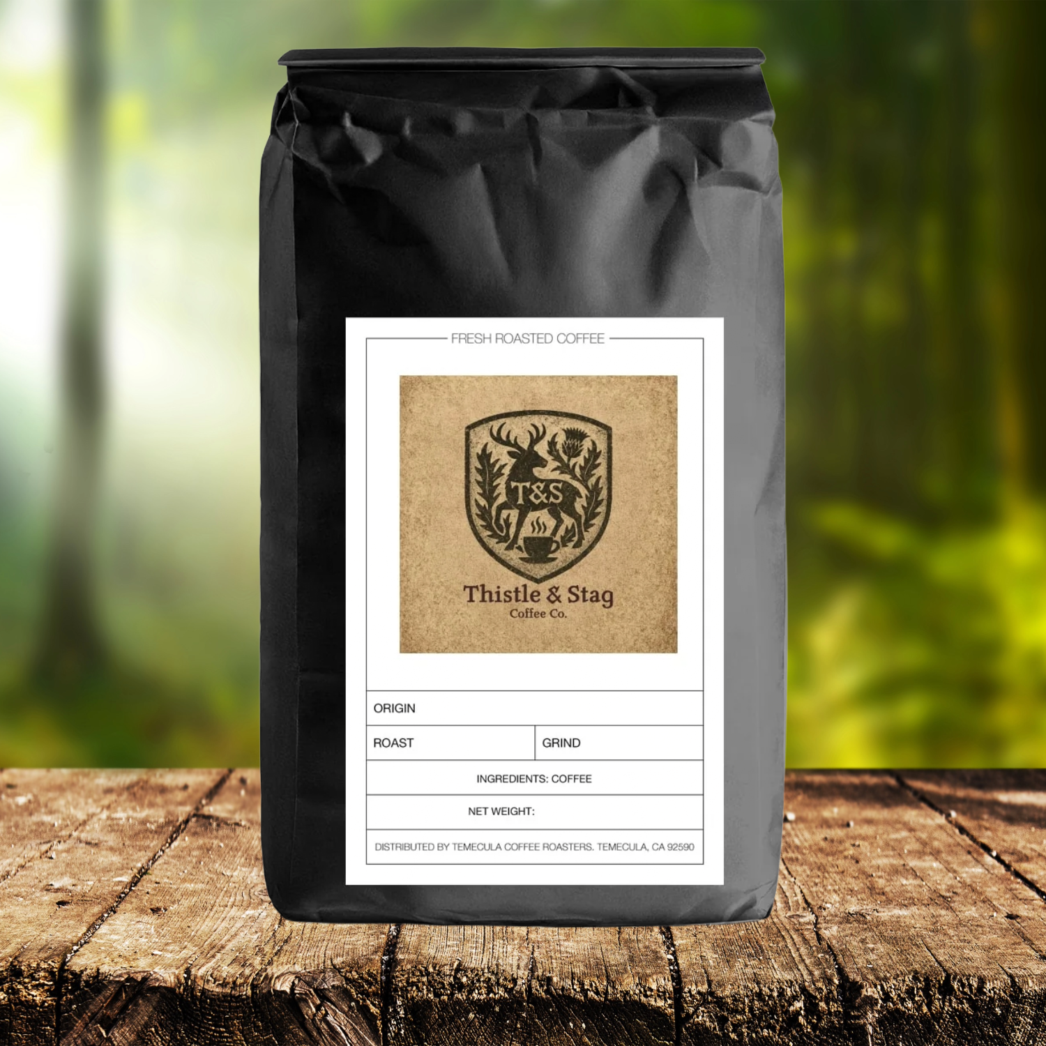 Black coffee bag with Thistle & Stag Coffee Co. label on a wooden surface with a blurred green background